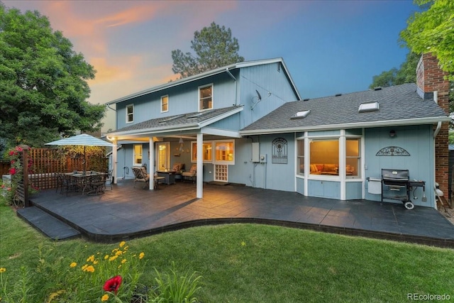 3765 E Easter Dr, Centennial, CO 80122 - back of house at dusk featuring a yard, a chimney, a patio area, and a shingled roof