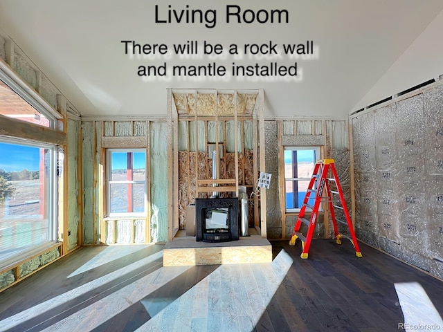 unfurnished living room featuring a wood stove, a wealth of natural light, and lofted ceiling