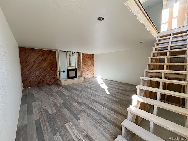 unfurnished living room featuring wood walls and dark wood-type flooring