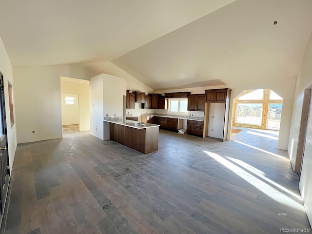 kitchen with kitchen peninsula, dark hardwood / wood-style flooring, and high vaulted ceiling