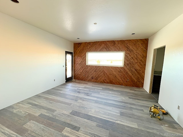 empty room with wood-type flooring and wooden walls