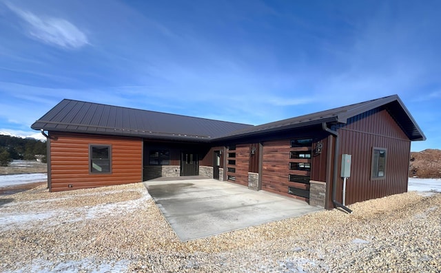 view of front facade featuring an exterior structure, metal roof, a garage, driveway, and an outdoor structure