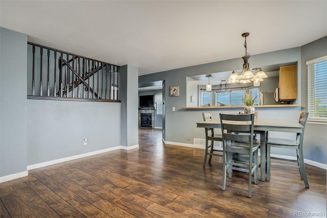 8060 Willowick Ct, Colorado Springs, CO 80925 - dining area featuring a chandelier, wood finished floors, baseboards, stairs, and a glass covered fireplace
