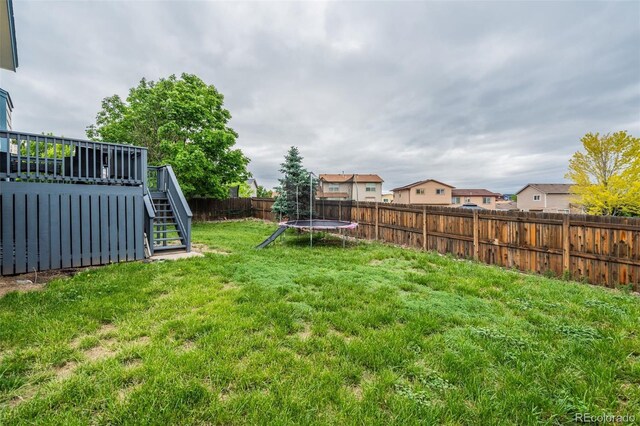 8060 Willowick Ct, Colorado Springs, CO 80925 - view of yard with a trampoline, stairway, and a wooden deck
