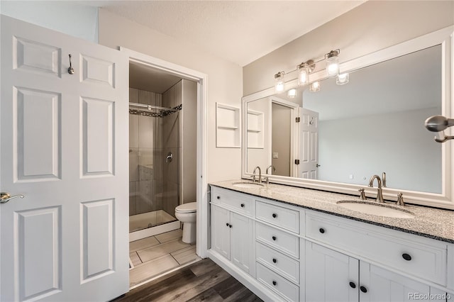 bathroom with wood-type flooring, a shower with door, vanity, a textured ceiling, and toilet