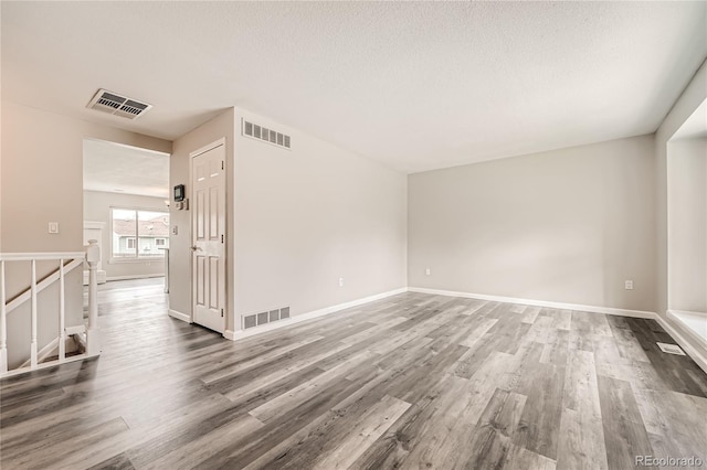 unfurnished room featuring wood-type flooring and a textured ceiling