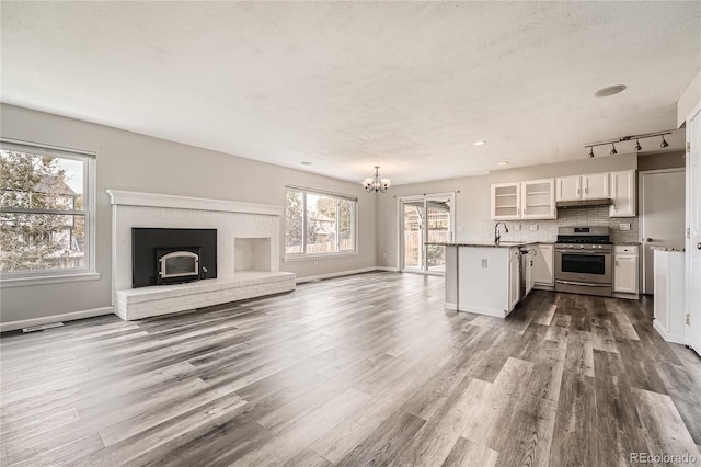 unfurnished living room with a textured ceiling, dark wood-type flooring, sink, and a notable chandelier