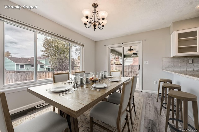 dining area with hardwood / wood-style floors, a textured ceiling, and an inviting chandelier