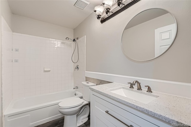 full bathroom with hardwood / wood-style flooring, vanity, tiled shower / bath combo, and toilet