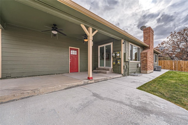 doorway to property with a lawn, ceiling fan, and central AC