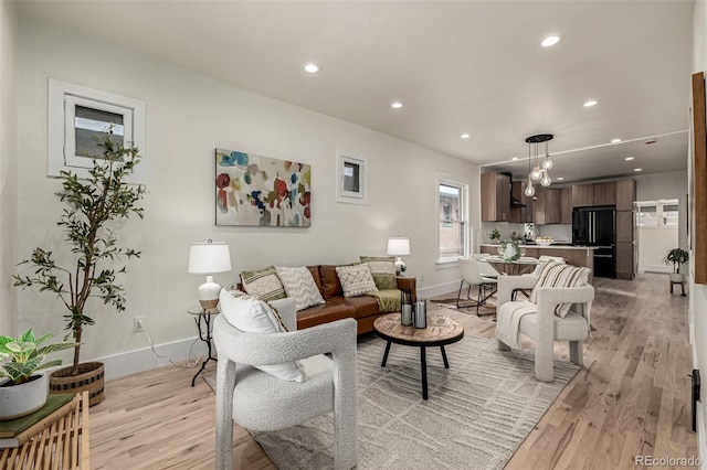 living room with baseboards, recessed lighting, and light wood-style flooring