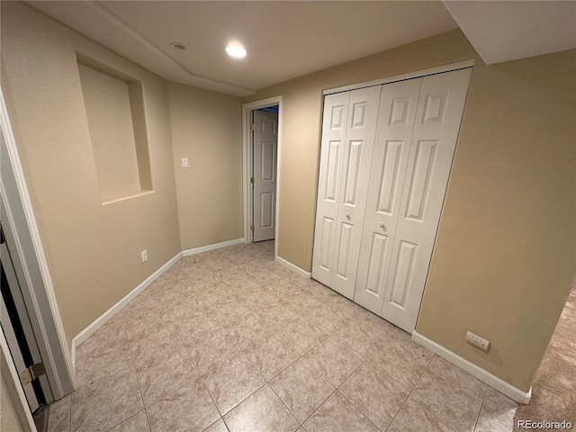 unfurnished bedroom with a closet, baseboards, light tile patterned flooring, and recessed lighting