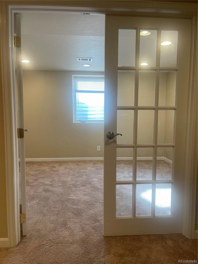 carpeted spare room with visible vents and baseboards