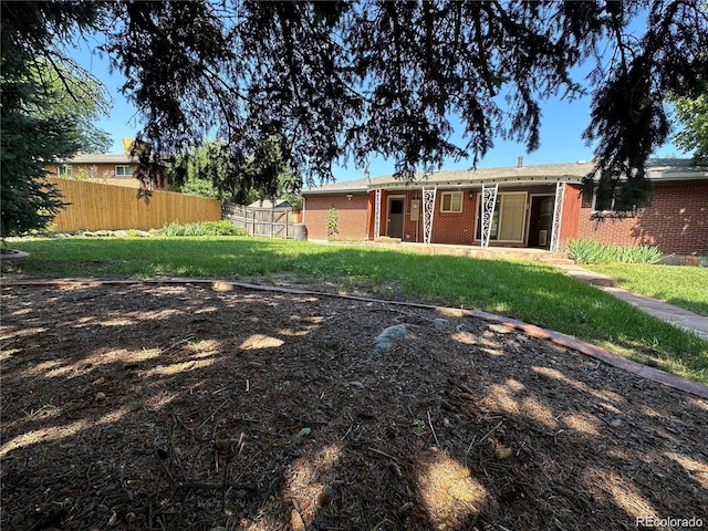 back of property featuring a lawn, brick siding, and fence