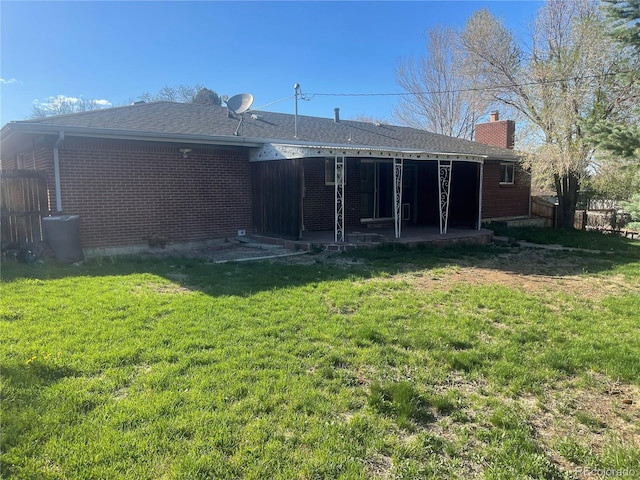 rear view of house featuring a patio, a chimney, fence, a yard, and brick siding