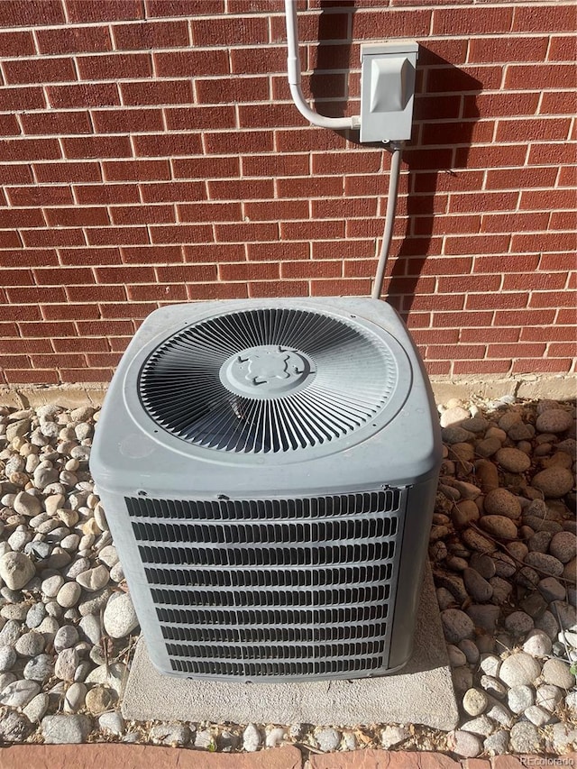 exterior details featuring cooling unit and brick siding