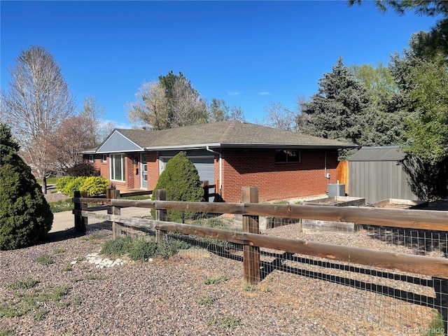 view of front of property featuring fence, brick siding, a garage, a shed, and an outbuilding