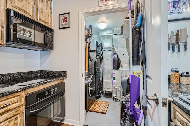 kitchen with dark stone counters, concrete floors, and black appliances