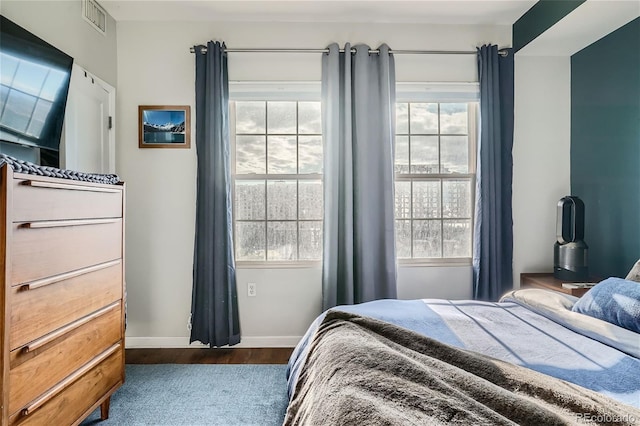 bedroom with multiple windows and dark hardwood / wood-style flooring