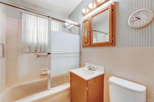 full bath with toilet, shower / bath combination with glass door, vanity, wainscoting, and wallpapered walls