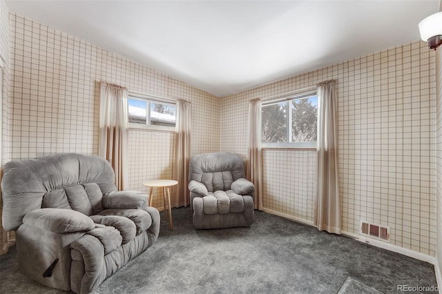 sitting room featuring lofted ceiling, visible vents, tile walls, and dark colored carpet