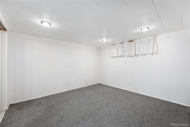 unfurnished room with dark carpet and baseboards