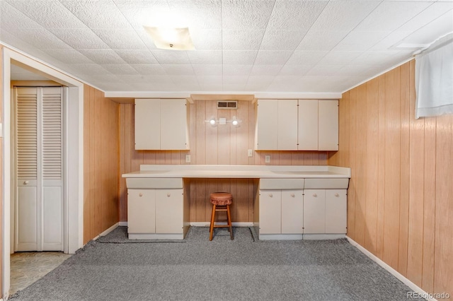 kitchen featuring light colored carpet, visible vents, light countertops, and wooden walls