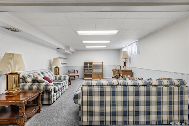 living room featuring carpet floors, visible vents, a paneled ceiling, and wainscoting