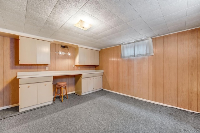 interior space with light carpet, wood walls, visible vents, and baseboards