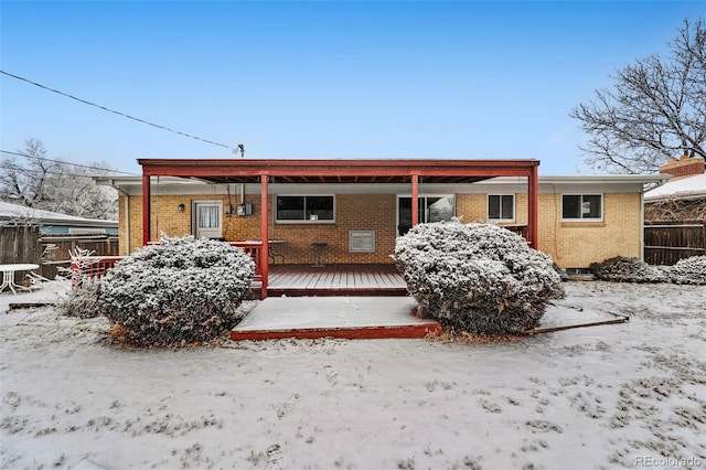 single story home featuring brick siding, fence, and a wooden deck