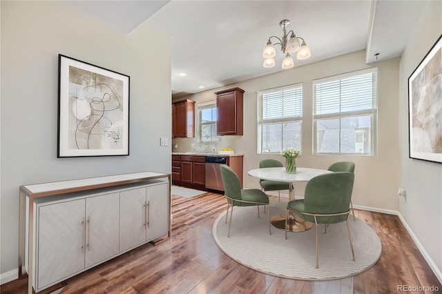 dining space featuring hardwood / wood-style flooring, a wealth of natural light, a notable chandelier, and sink