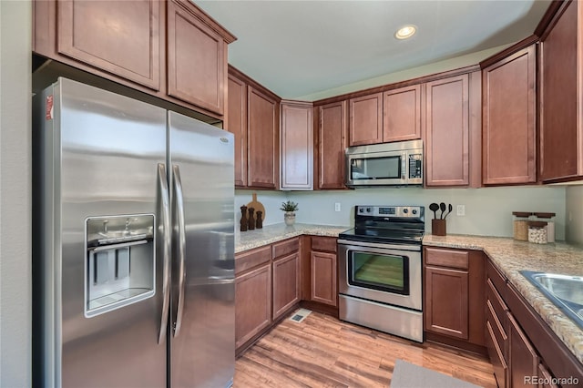 kitchen with light stone counters, light hardwood / wood-style flooring, sink, and appliances with stainless steel finishes