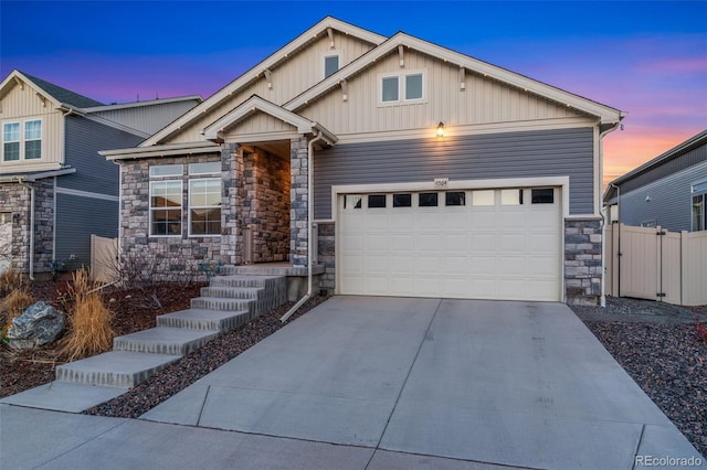 craftsman inspired home featuring driveway, a gate, stone siding, fence, and board and batten siding