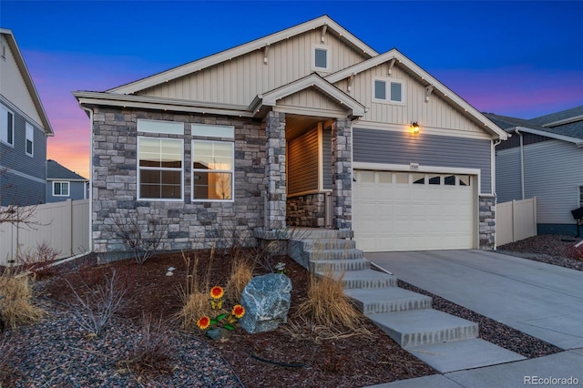 view of front of home featuring stone siding, fence, board and batten siding, concrete driveway, and a garage