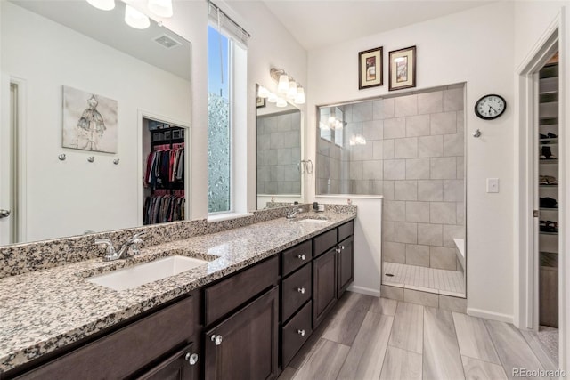 full bathroom featuring a sink, visible vents, double vanity, and a walk in shower