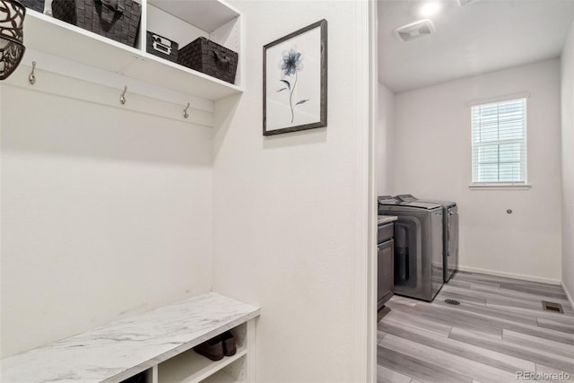 mudroom featuring visible vents, baseboards, light wood-style floors, and washing machine and dryer