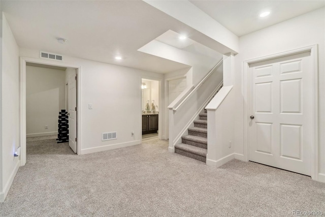 below grade area featuring stairway, visible vents, and carpet floors