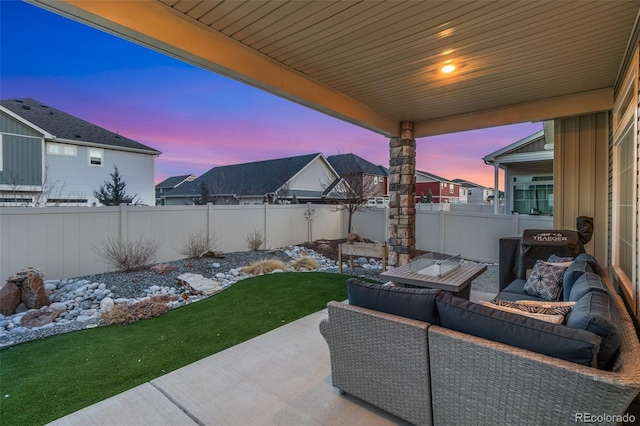 patio terrace at dusk with a yard, outdoor lounge area, and a fenced backyard