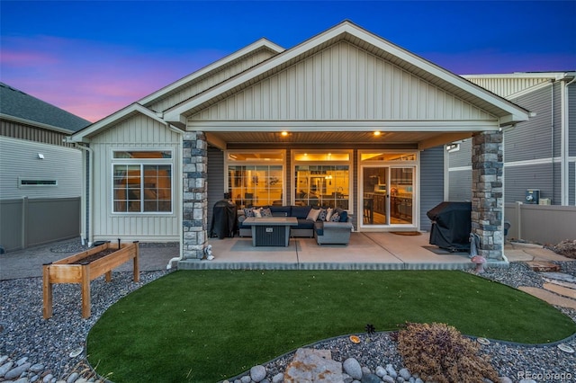 back of house featuring a lawn, a patio, fence, board and batten siding, and outdoor lounge area