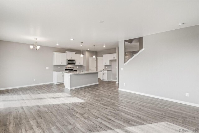 13477 Valentia St, Thornton, CO 80602 - unfurnished living room with a chandelier, light wood-style floors, baseboards, and recessed lighting