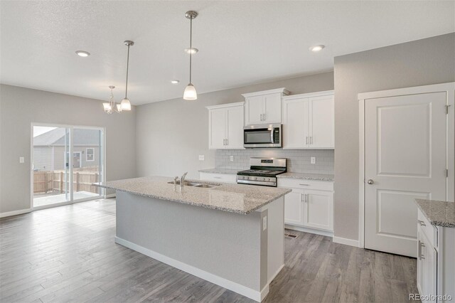 13477 Valentia St, Thornton, CO 80602 - kitchen featuring stainless steel appliances, a sink, light wood-style floors, backsplash, and a center island with sink