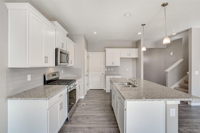 13477 Valentia St, Thornton, CO 80602 - kitchen with appliances with stainless steel finishes, a sink, wood finished floors, backsplash, and recessed lighting