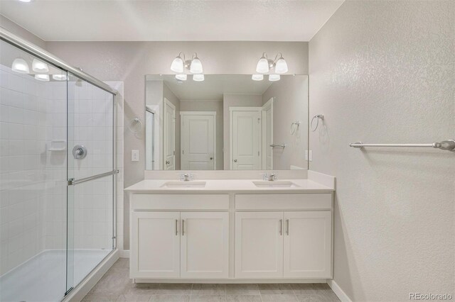 13477 Valentia St, Thornton, CO 80602 - full bathroom featuring a textured wall, a shower stall, double vanity, and baseboards