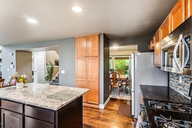 kitchen featuring dark wood-type flooring, gas range oven, recessed lighting, stainless steel microwave, and light stone counters