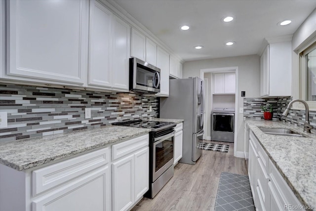 7427 S Ames Ct, Littleton, CO 80128 - kitchen with appliances with stainless steel finishes, washer / clothes dryer, white cabinetry, backsplash, and light wood-type flooring