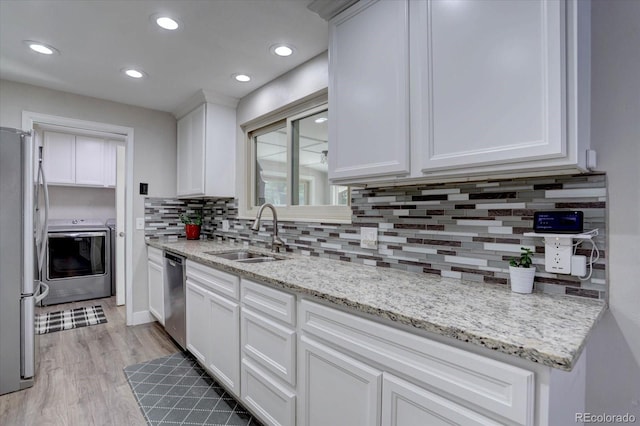 7427 S Ames Ct, Littleton, CO 80128 - kitchen with stainless steel appliances, tasteful backsplash, white cabinetry, light wood-type flooring, and washer and clothes dryer