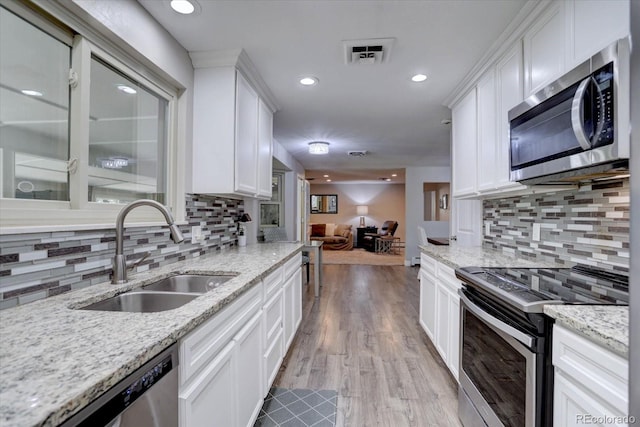7427 S Ames Ct, Littleton, CO 80128 - kitchen with stainless steel appliances, tasteful backsplash, white cabinetry, recessed lighting, and light stone counters