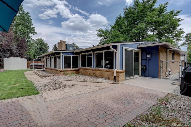 7427 S Ames Ct, Littleton, CO 80128 - rear view of house with a sunroom, brick siding, a shed, and a chimney