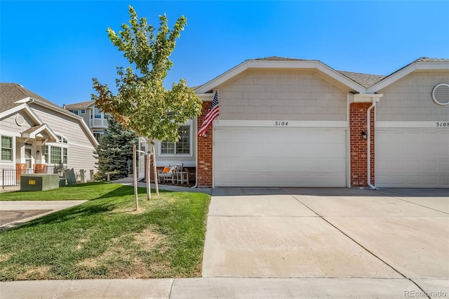 view of front of home with a front lawn, a garage, brick siding, and concrete driveway