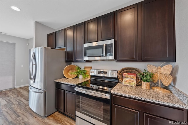 kitchen featuring light stone counters, dark brown cabinetry, stainless steel appliances, and light hardwood / wood-style flooring